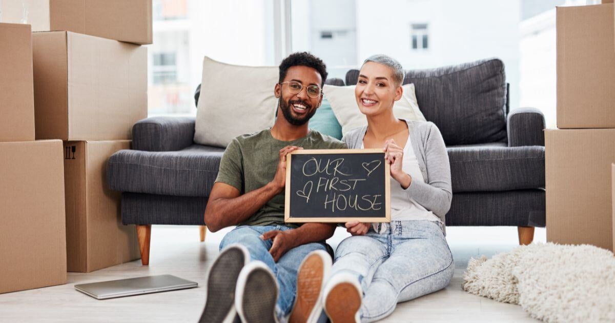 First-time homebuyers with 'Our First House' sign – FHA loan with low down payment and flexible credit requirements.